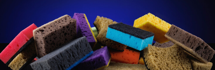 Background of mixed colorful sponges for washing dishes. Household cleaning sponge on a blue background.