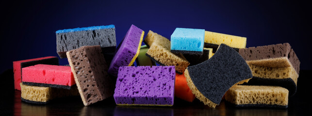 Background of mixed colorful sponges for washing dishes. Household cleaning sponge on a blue background.