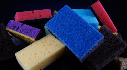 Background of mixed colorful sponges for washing dishes. Household cleaning sponge on a blue background.