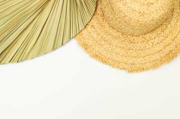 Top view of straw hat and dried palm leaf on white background. Summer fashion, vacation and beach...