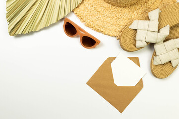 Top view of straw hat, dried palm leaf, slippers, sunglass on white background. Brown kraft...