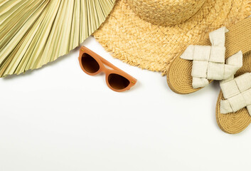 Top view of straw hat, dried palm leaf, slippers and sunglass on white background. Summer fashion,...
