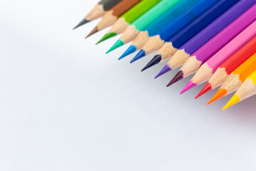 Close-up of colored pencils placed diagonally on a white background. Leave space to use as a background image.