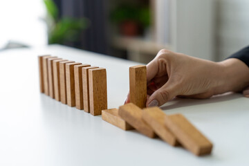 The manager's hands are stopping the falling dominoes to prevent their total collapse and ensure...