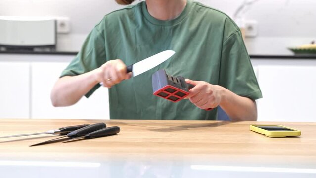 Close-up of woman sharpening knife with special knife sharpener at home	