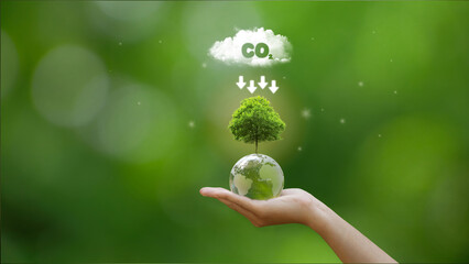 Hand holding green globe with map and have CO2 white cloud on top. Reduce CO2 emissions to limit...