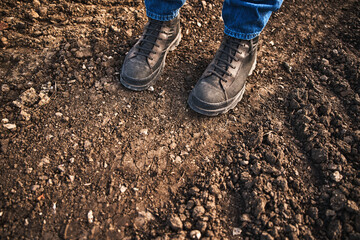 Closeup of farmer's boots standing on countryside dirt road