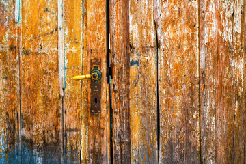 Old worn wooden entrance door with flaking paint as grunge texture