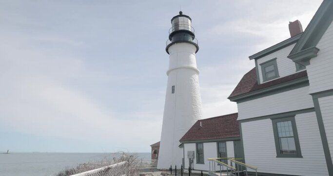 Beautiful up close view of the Portland Maine Head Light light house during a beautiful spring day with waves rolling into the rocky shore in 4k.