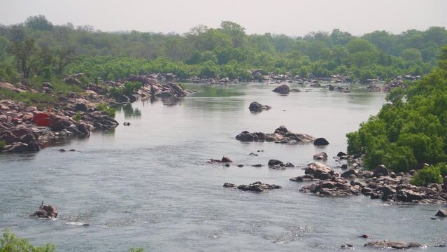 Pan shot of Betwa river flowing through rocky terrain on the banks of forest near Orchha in Madhya Pradesh India