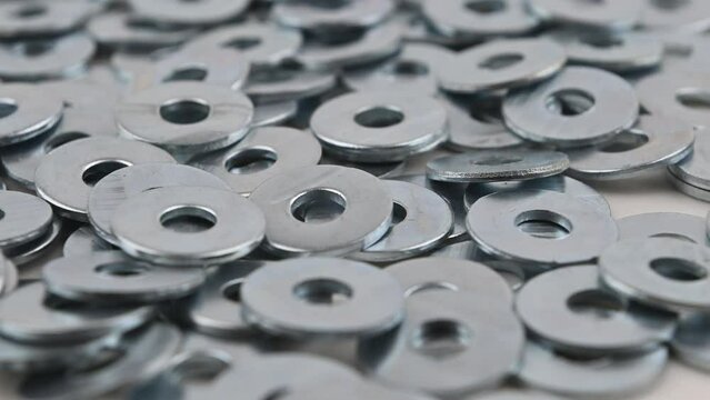 Set of metal washers in the foreground. Movement with rotation. Close-up, side view, small depth of field.