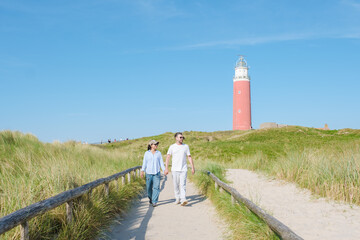 A couple leisurely walks along a path next to a charming lighthouse on the picturesque island of...