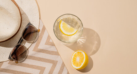 Summer layout with lemonade, fresh citrus fruits, hat and sunglasses on a beach towel on a beige...