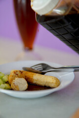 A portion of Indonesian Dish Pempek containing Lenjer and Adaan with a bottle full of savory spicy delicious pempek seasoning ready to pour.