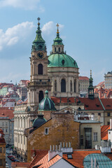 Fototapeta na wymiar Church of St. Nicholas (built 1732-1737) against the backdrop of the roofs of the capital of the Czech Republic - the city of Prague