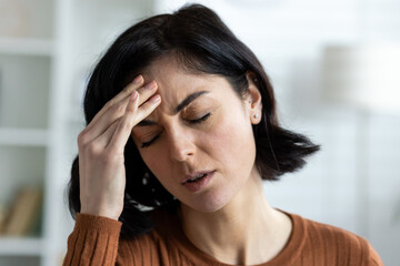 Young woman experiencing a headache, holding her forehead in discomfort