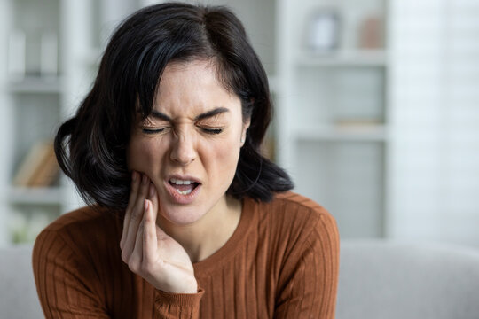 Woman experiencing severe toothache at home, displaying pain and discomfort