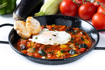 Vegetable pisto manchego with tomatoes, zucchini, peppers, onions,eggplant and egg, served in frying pan isolated on white background