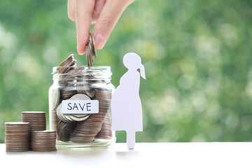 Pregnant woman and coin money in the glass bottle on natural green background,Save money for...