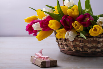 A close-up of a basket with colorful blooming tulips. Holiday card. Copyspace.