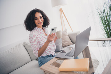 Photo of adorable pretty woman sitting on sofa reading social media white light interior living room indoors