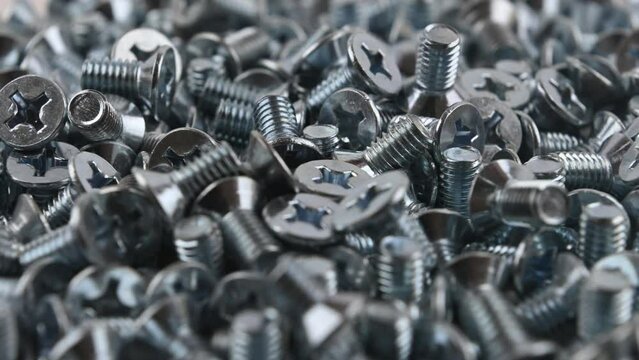 Falling of metric countersunk M6 threaded bolts. Movement with rotation. Close-up, side view, small depth of field.