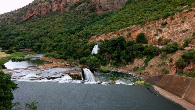 View from the dam wall, looking out over the sluice at Hartbeespoort dam showing the sloping rock layers and a number of cascades and waterfalls downstream from the wall of this dam in South Africa.