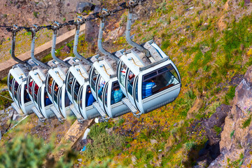 Fira, Santorini island, Greece close-up cable car cabins from old port, high volcanic rocks