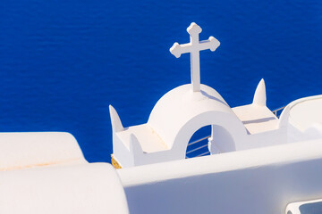 Santorini, Greece iconic view of white church cross and bell tower, blue sea background