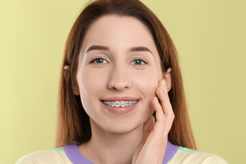 Portrait of smiling woman with dental braces on light green background