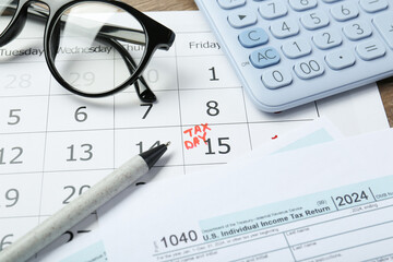 Calendar with date reminder about tax day, documents, pen, glasses and calculator on table, closeup