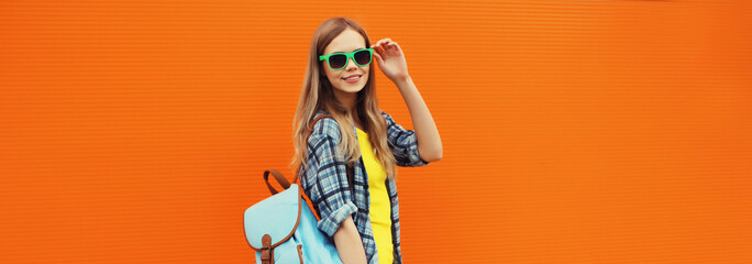 Summer portrait of happy cheerful stylish young woman in glasses posing on orange background
