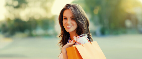 happy brunette young woman with shopping bags walking in the city