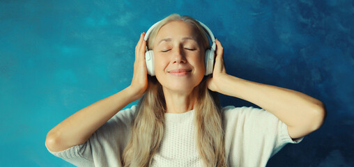 Portrait of happy relaxed middle aged woman listening to music with headphones