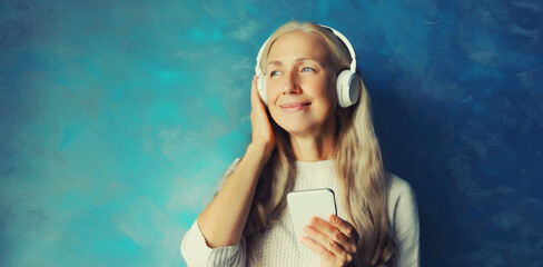 Portrait of happy smiling caucasian mature woman listening to music in headphones with smartphone