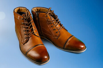 A pair of premium calfskin boots on a blue background. Horizontal shot.