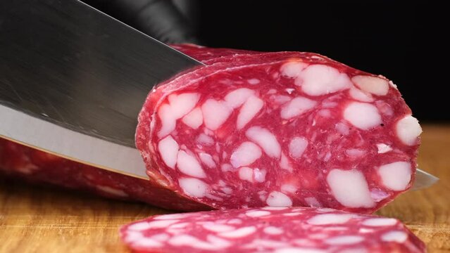 Process slicing sausages salami, closeup. Cured sausages