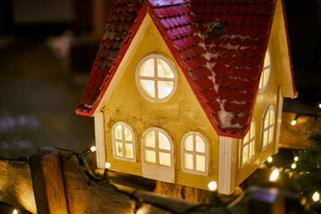 Christmas fairy tale house with warm glow windows at nighttime city street, symbolizes spirit of...