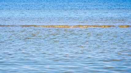 Reflections of clear water on a shallow sandy beach bottom.