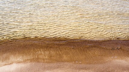 Reflections of clear water on a shallow sandy beach bottom. Clear water. Sandy shore.