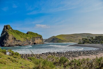 Idyllic landscape featuring a coastal beach in the foreground with a rolling green hill