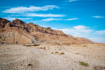 a long fence leading to some rocky terrain below blue skies