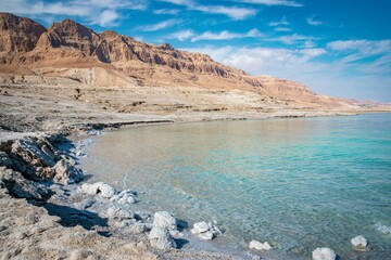 the view from the dead sea shore of an arid coastline with rocky mountains in the