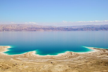 Obraz premium a blue body of water with a shoreline surrounded by white sand: dead sea