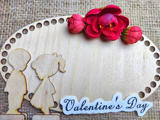 Wooden figurines of couple, inscription Valentine's Day, red flowers. Concept of holiday of love. Background, texture, place for text, copy space, frame