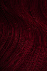 Dark red hair close-up as a background. Women's long brown hair. Beautifully styled wavy shiny...