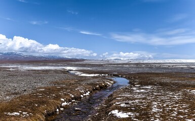 Small stream running through a field with mountains in the background