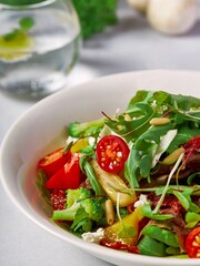 a salad with vegetables, olives, mushrooms and tomatoes in a bowl