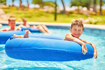 Picture of a small boy having fun in aquapark outdoor on tube