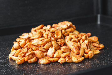 Close-up of spiced cashew nuts on a dark surface, highlighting their texture and seasoning